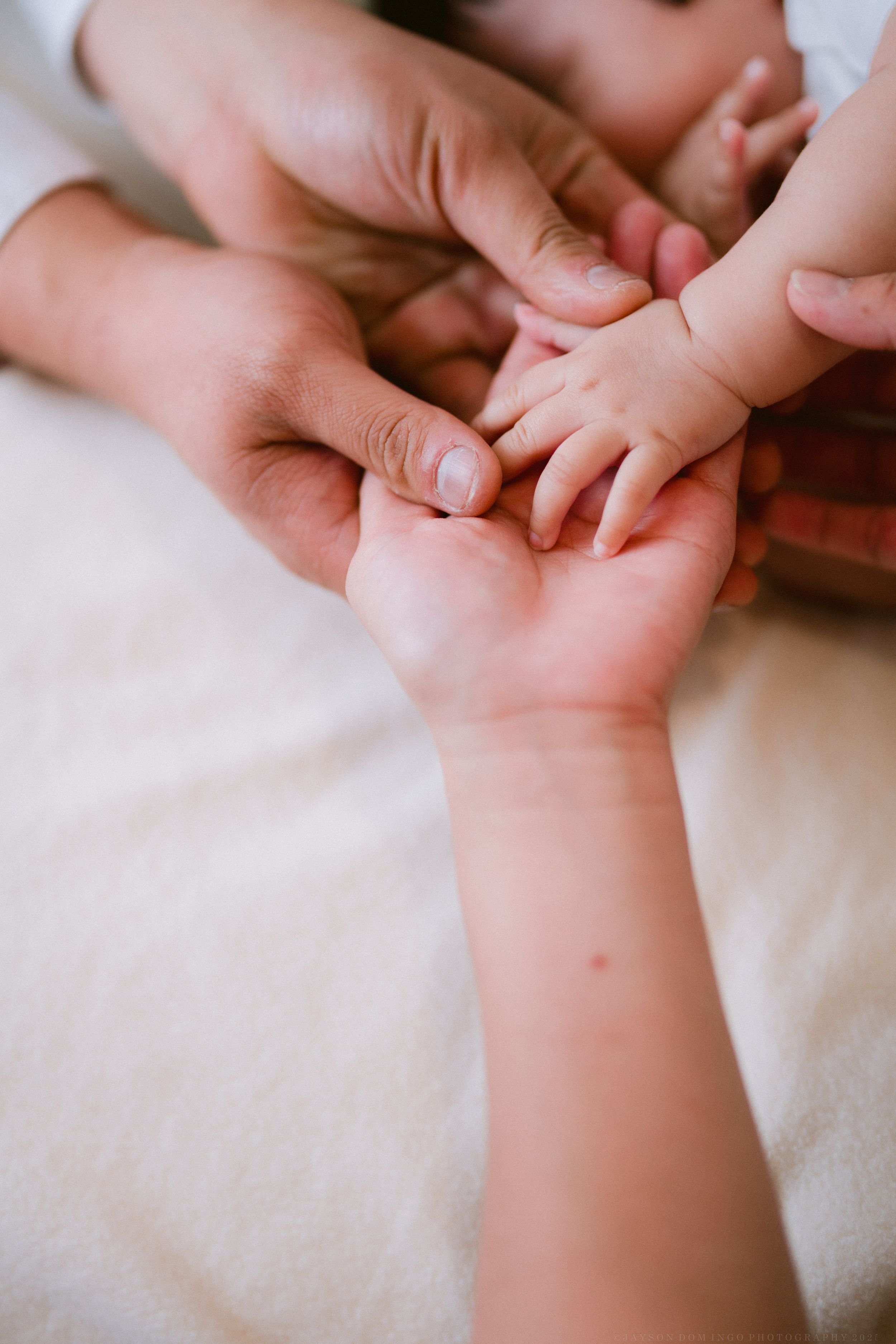Close-up shots of tiny baby hands and fingers against white fabric background.