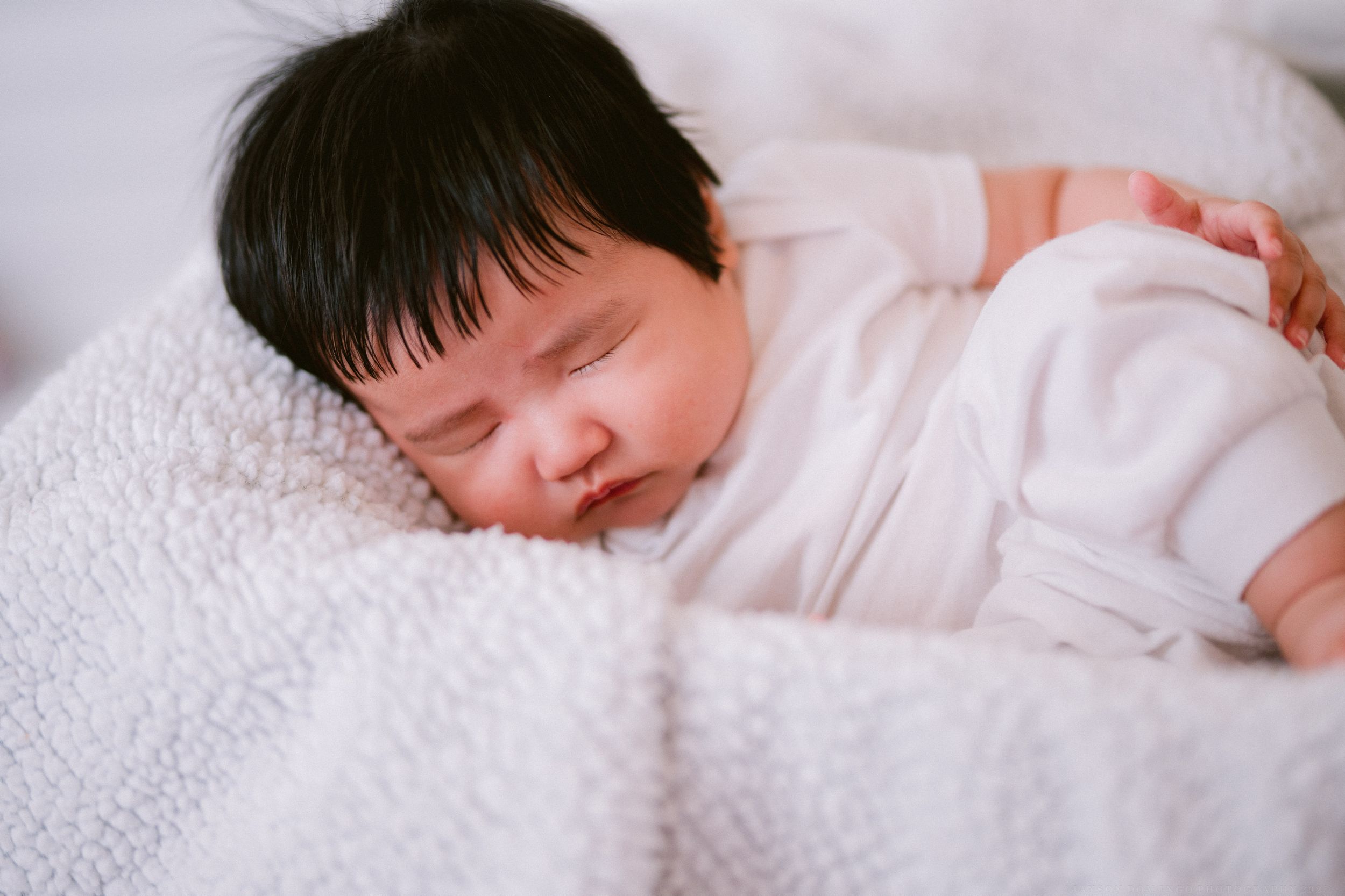 A sleeping baby in white clothing rests peacefully on soft bedding in a sequence of photos.
