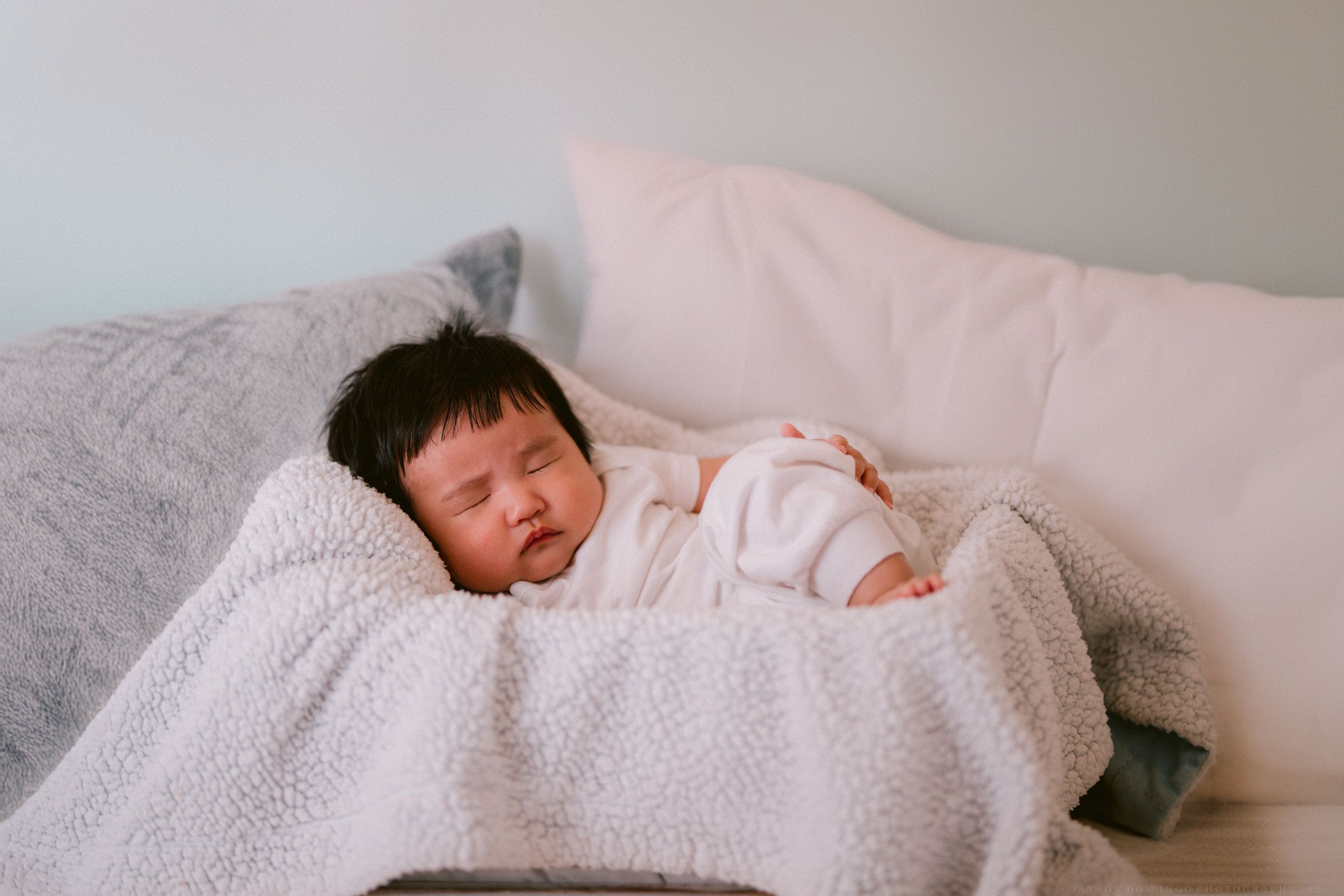 Baby napping peacefully under cozy white textured blanket.