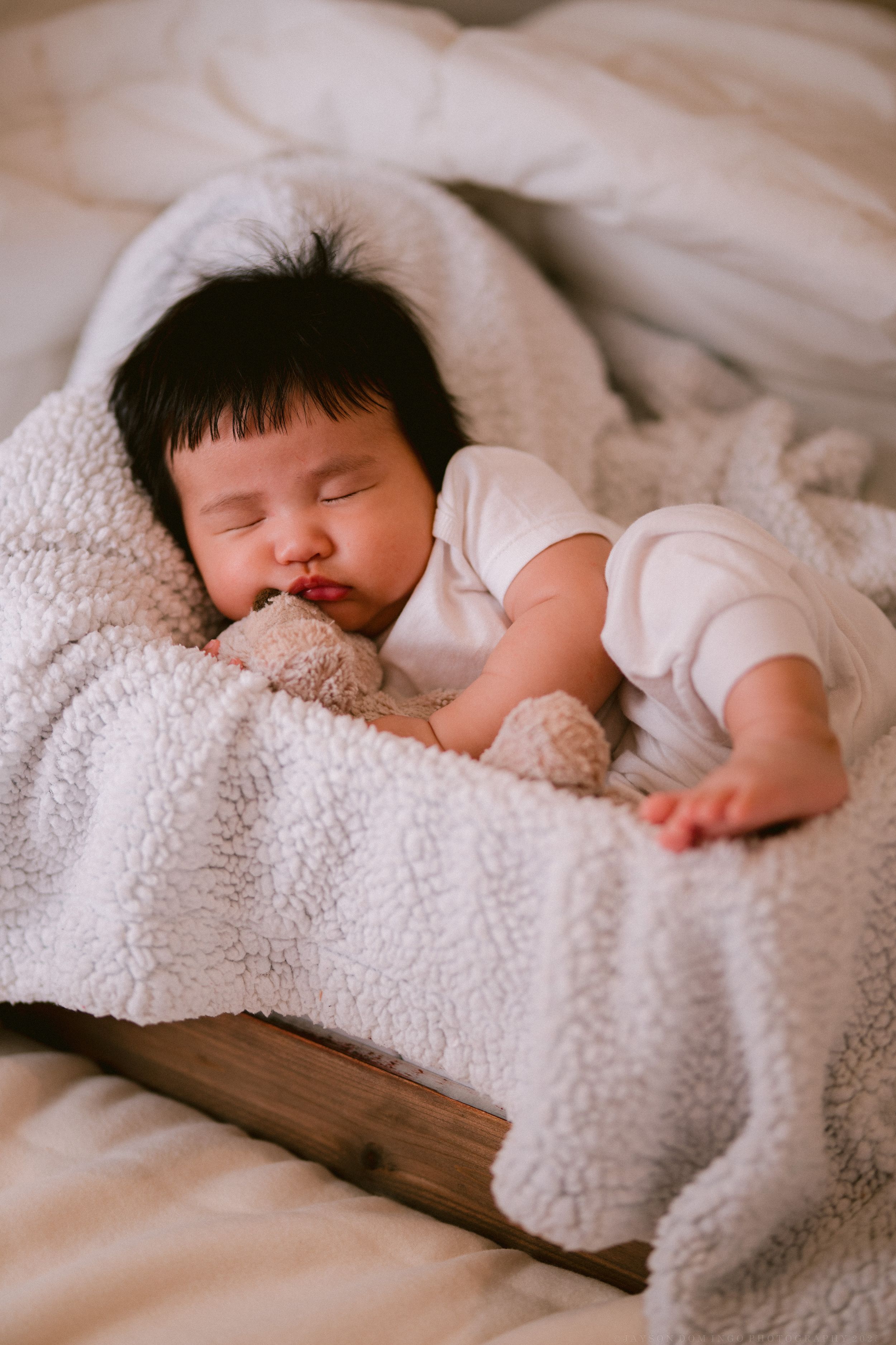 Peaceful baby napping on textured white blanket with natural lighting.