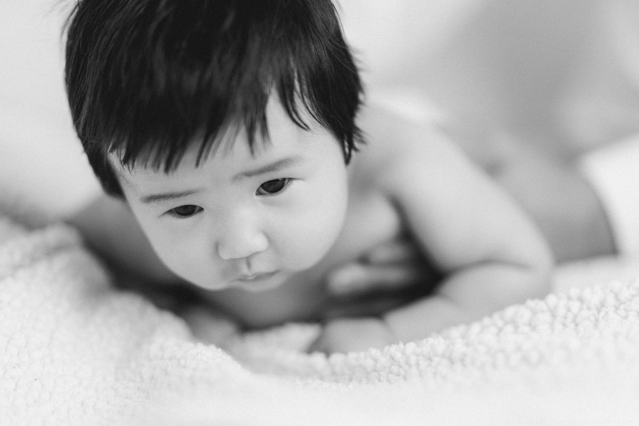 Peaceful sleeping baby rests on soft white blanket in black and white portrait.