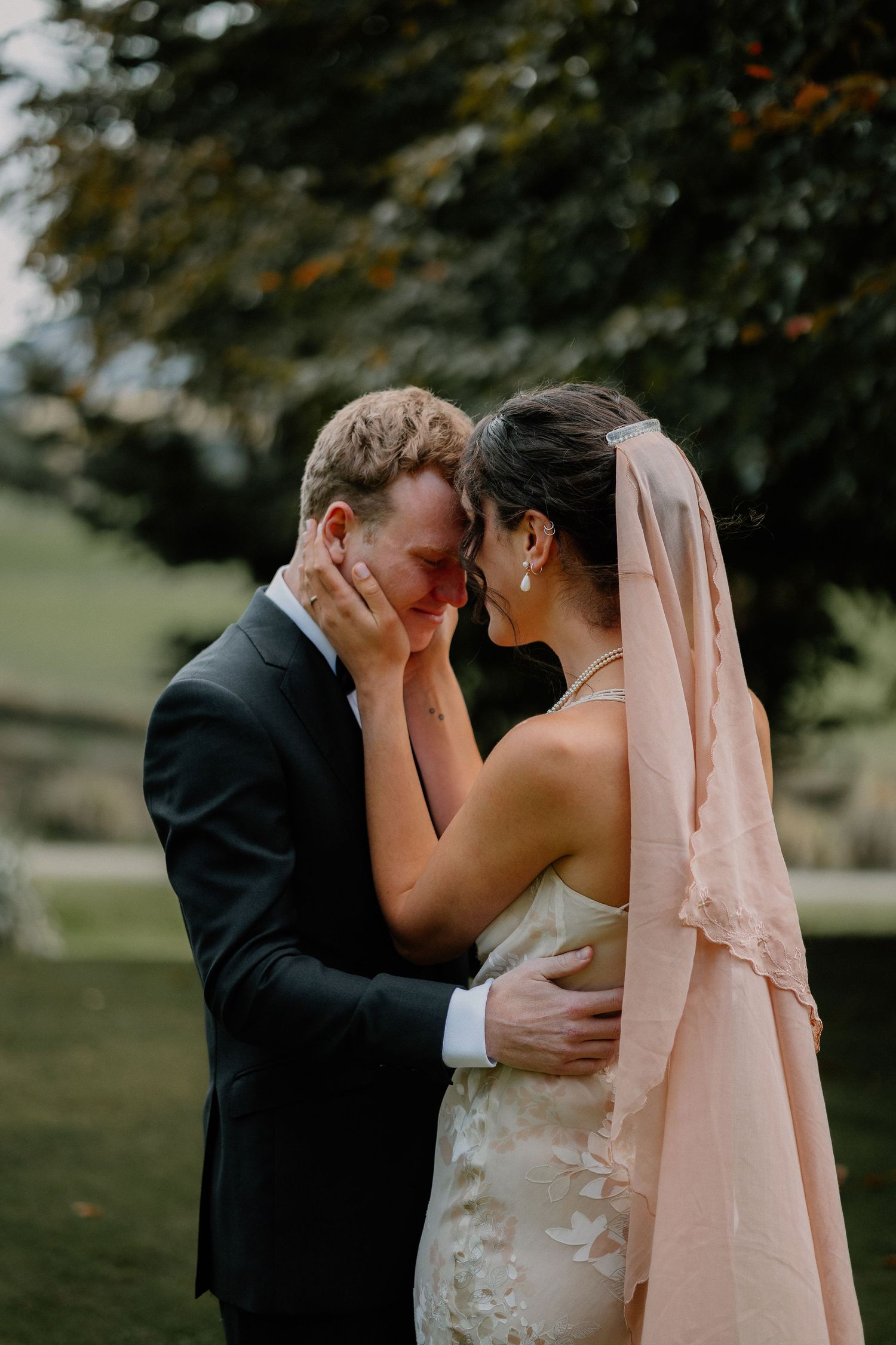 A romantic wedding couple shares an intimate kiss outdoors in a garden setting with soft lighting.