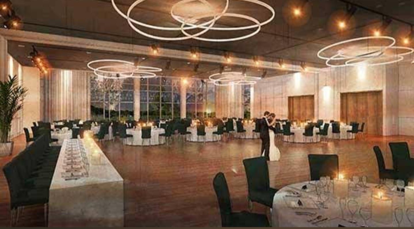 Modern circular lighting fixtures hang from the ceiling in an elegant ballroom setting.