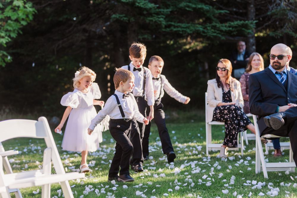 Wedding guests toss white flower petals during an outdoor ceremony celebration.