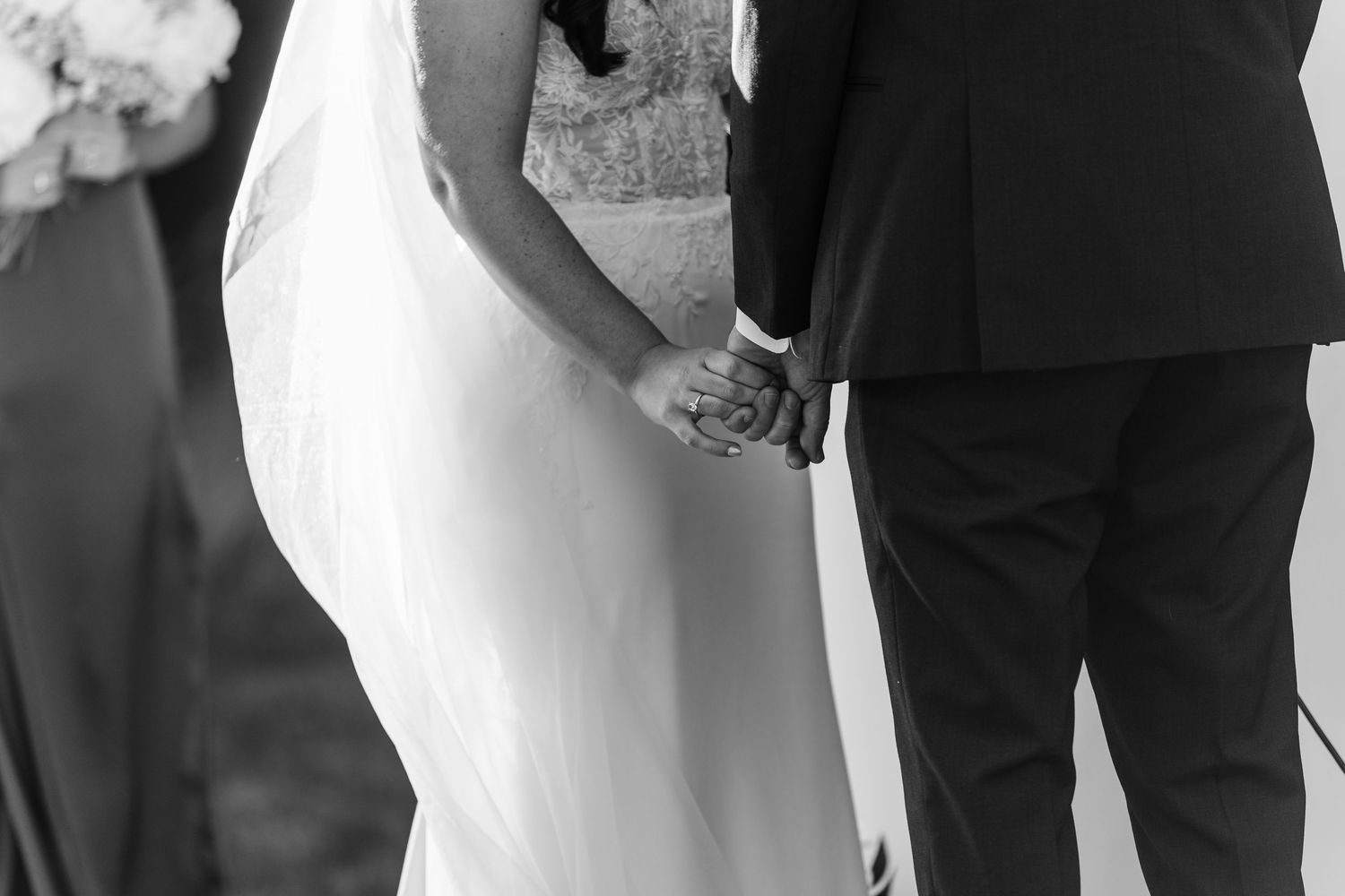 A wedding party stands in a row wearing formal black and white attire for a group photo.