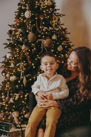 Heartwarming family moment captured in front of illuminated Christmas tree with white and gold decorations.