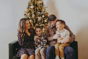 A group gathers around a decorated Christmas tree in a cozy living room during the holiday season.