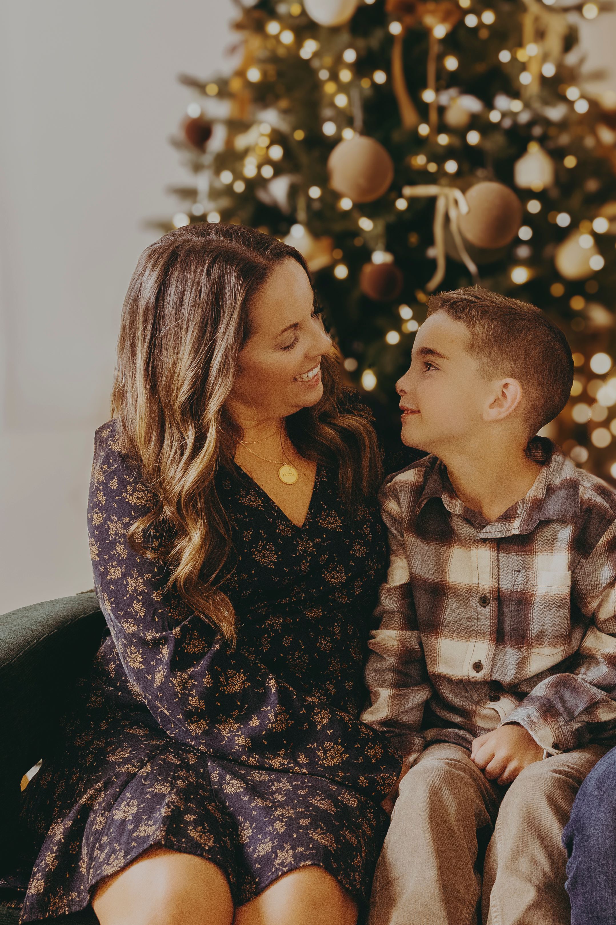 A couple shares intimate moments in front of a Christmas tree while wearing winter holiday attire.