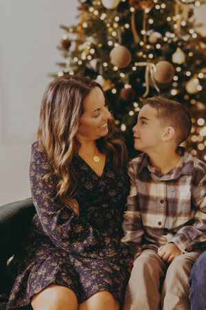 A couple shares intimate moments in front of a Christmas tree while wearing winter holiday attire.