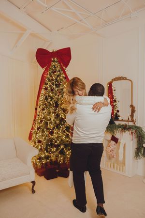 Multiple shots of people arranging Christmas decorations near a glowing tree with a large red bow.