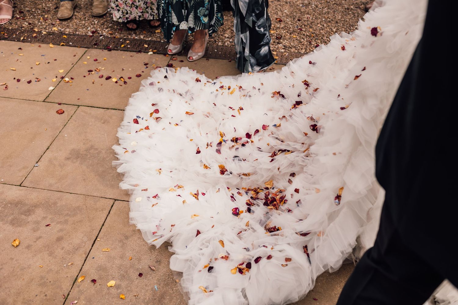 Wedding guests shower the newlyweds with confetti outside a historic brick building during a joyous celebration.