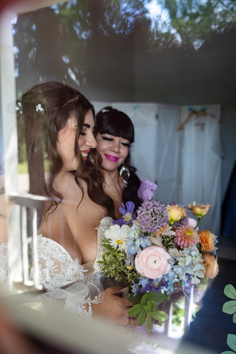 Two people share an intimate moment surrounded by colorful wedding flowers and white decor.