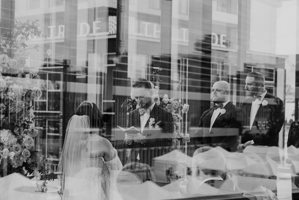 Black and white panoramic photograph showing reflective glass office building exterior with architectural details.