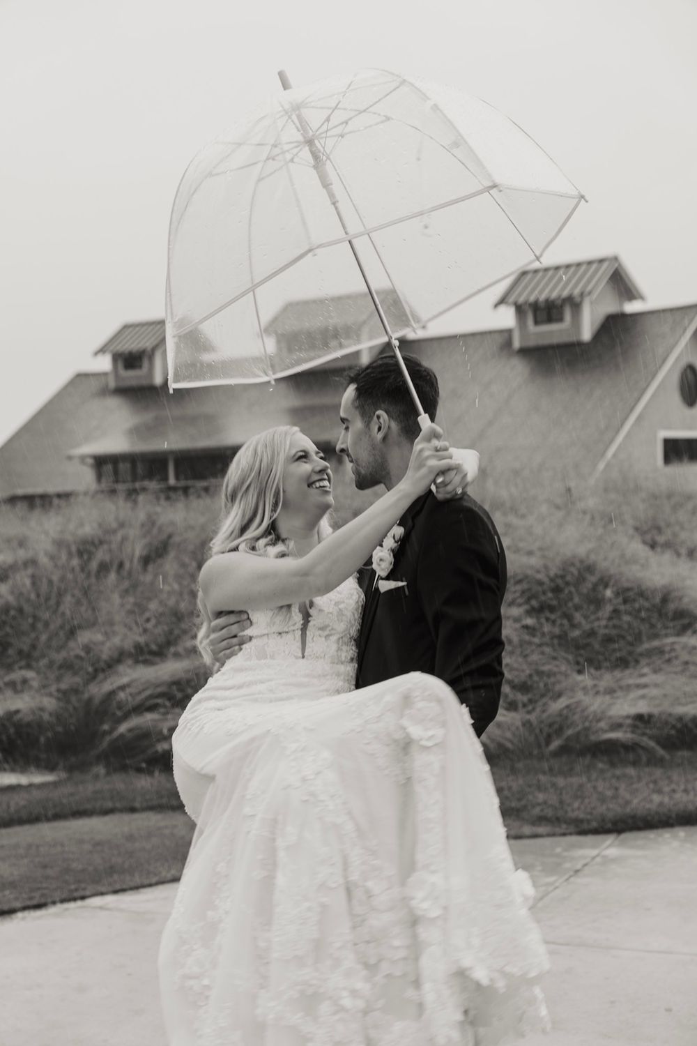 A couple in wedding attire shares romantic moments under clear umbrellas in a series of black and white photographs.