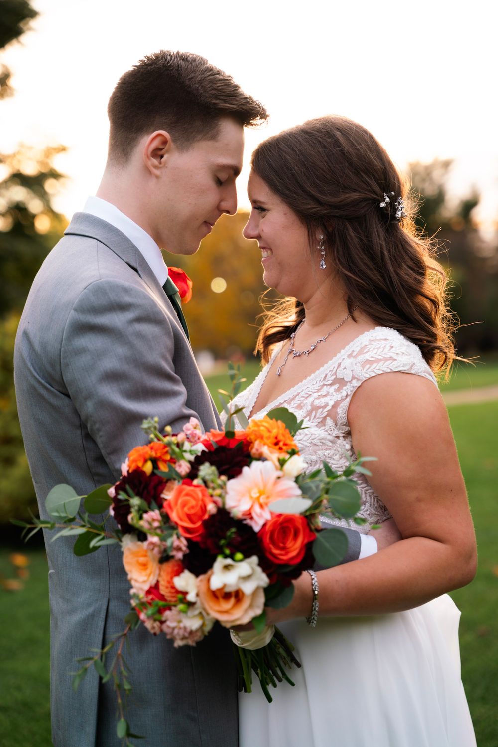 A romantic sunset wedding portrait series featuring a couple with a vibrant orange and pink floral bouquet.