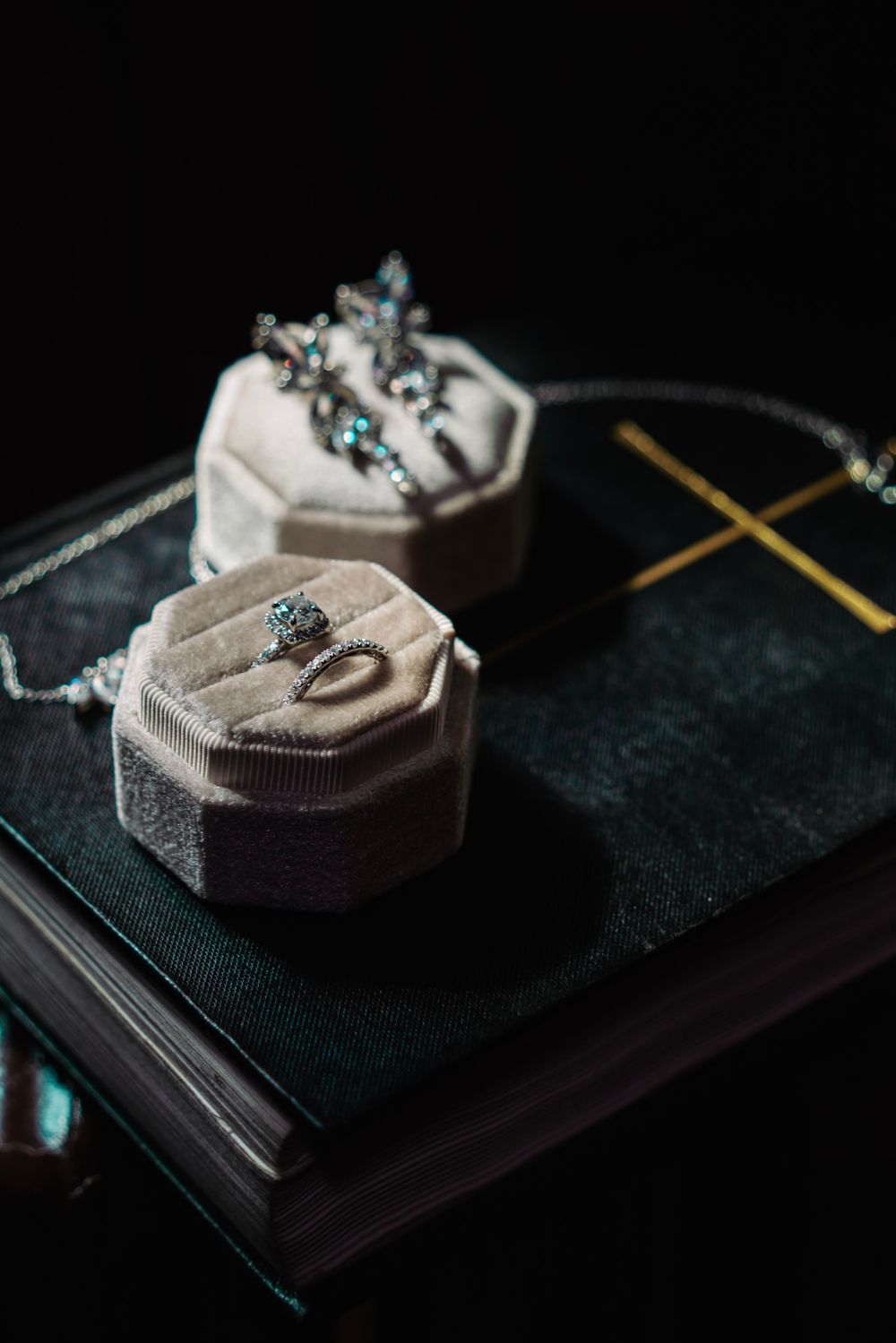 Elegant jewelry displayed on gray velvet ring holders against a dark background with gold accents.