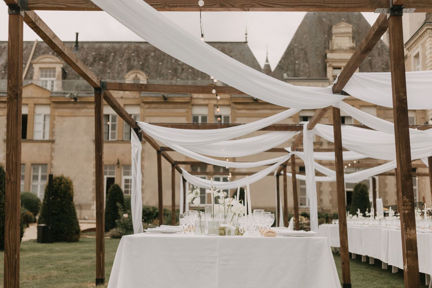 White fabric draping creates an elegant outdoor reception space at a historic venue.