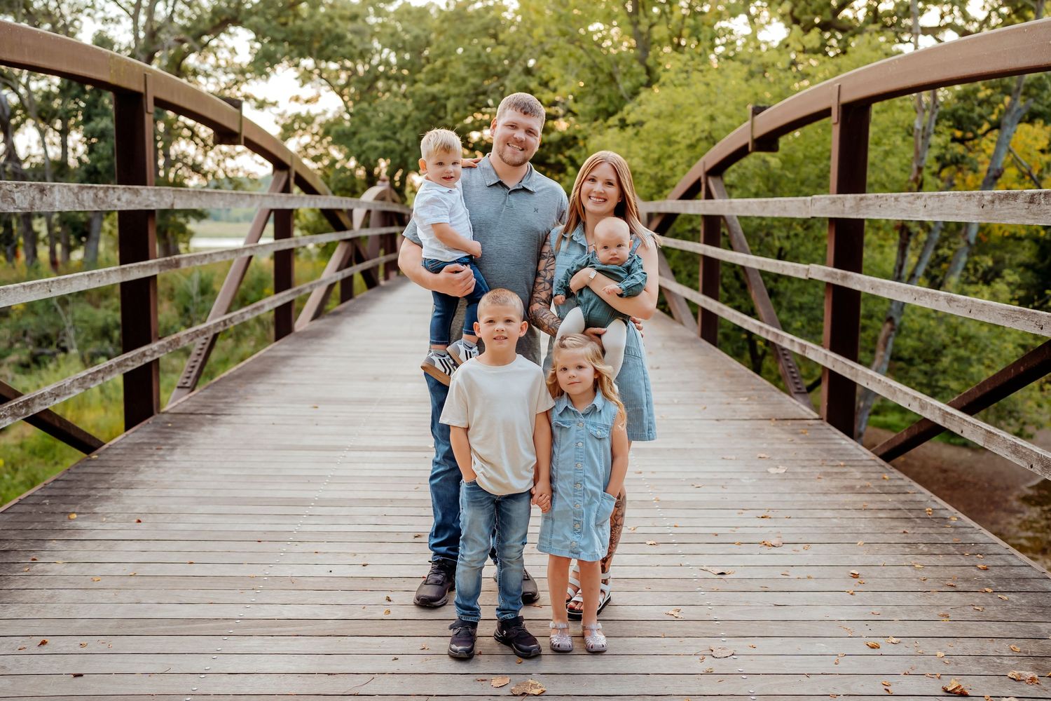 Family walking together on a wooden bridge pathway through a scenic natural area.