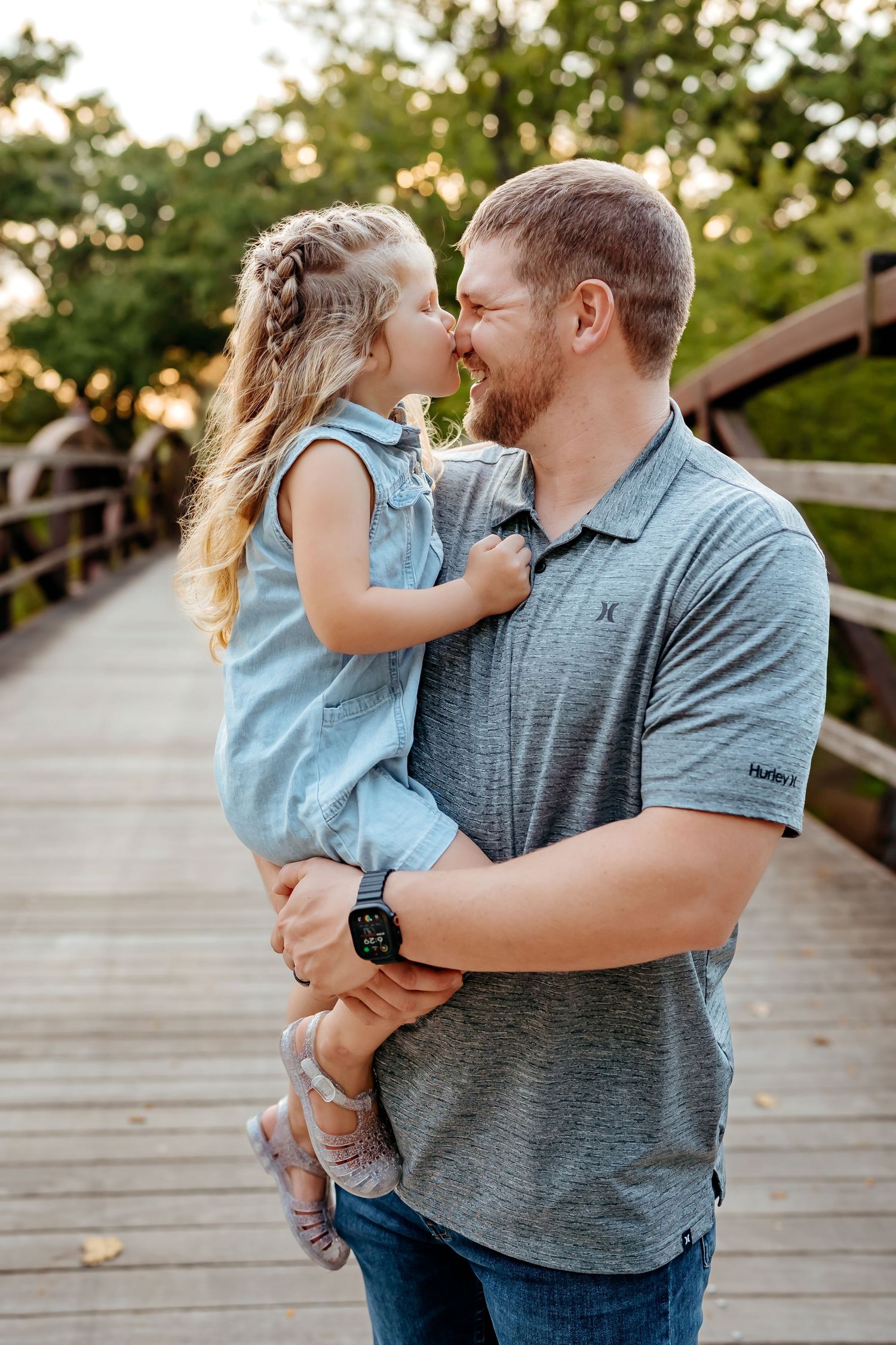 A tender moment between parent and child sharing affectionate interactions on a wooden bridge at sunset.