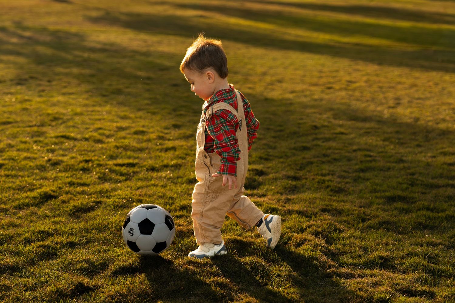 A sequence of photos shows a toddler in a pink dress chasing after a soccer ball in a sunlit grassy field.