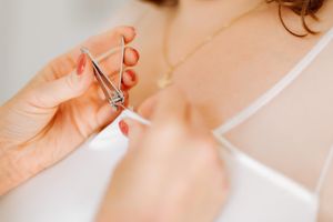 détail de préparation de mariage la mariée qui enlève un fil avec un coupe-ongle