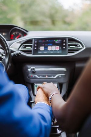 mariés qui se tiennent la main dans la voiture pour leur mariage