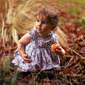 photo d'une petite fille qui tient une pomme dans le parc de madame elisabeth à versailles
