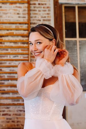 mariée qui met sa boucle d'oreille pendant le reportage des préparatifs