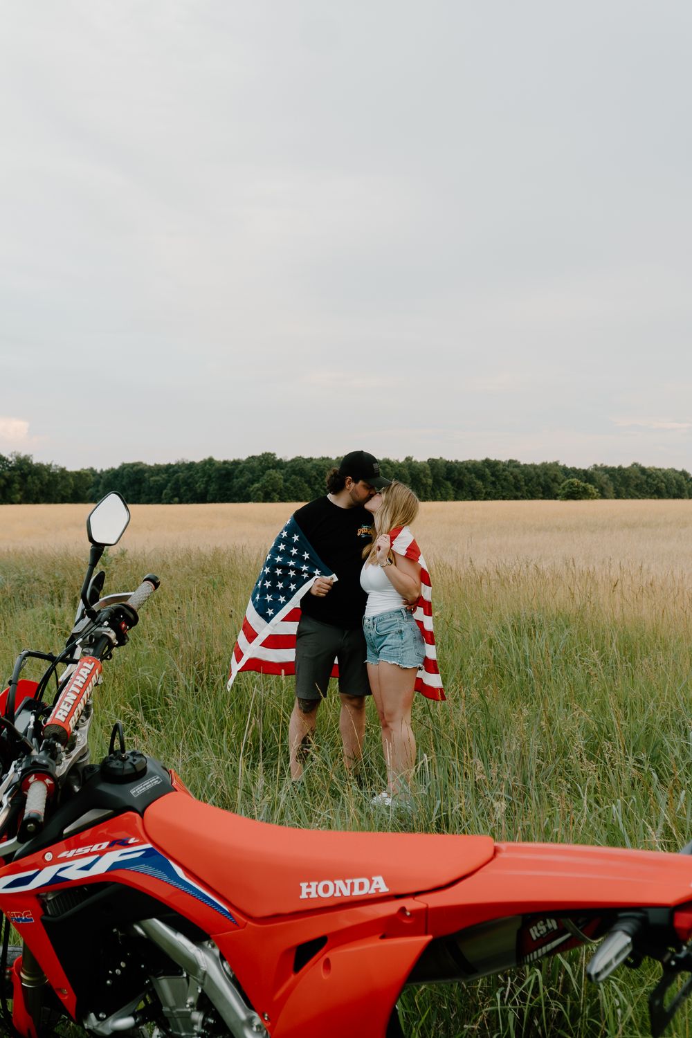A red Honda motorcycle parked in a grassy field with American flag decorations.