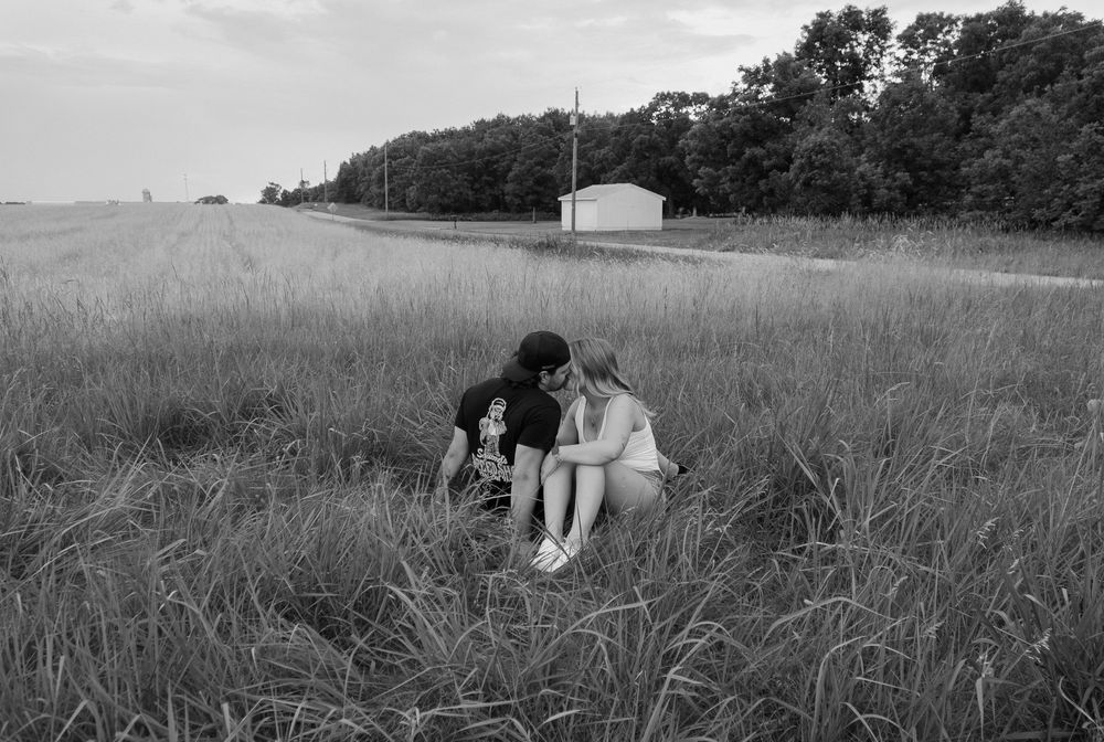 Black and white photo series showing a couple embracing in a grassy meadow at sunset.