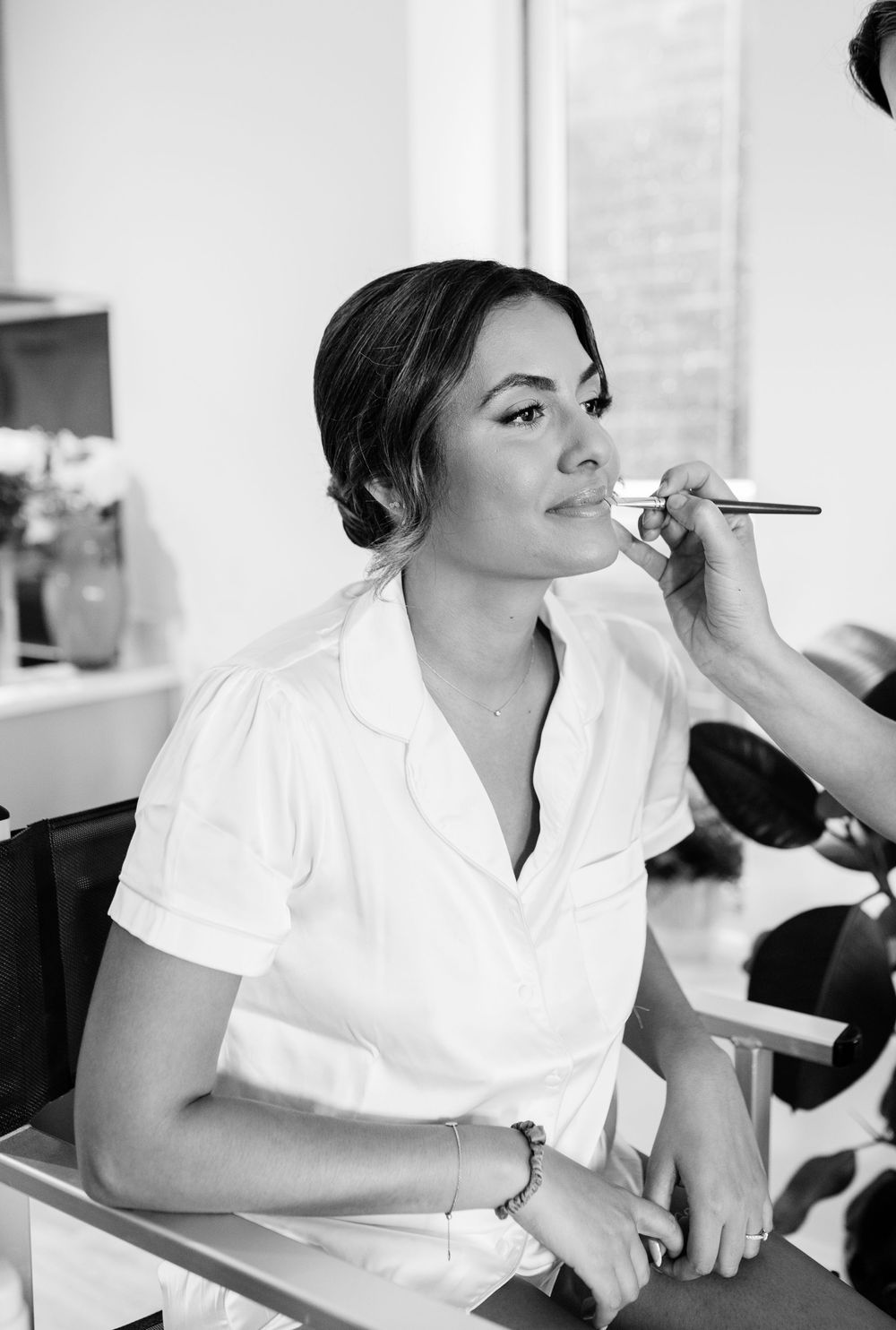 Black and white photos capturing makeup application moments before the wedding.