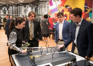 People gather around interactive digital displays at a modern retail or exhibition space with bright lighting.