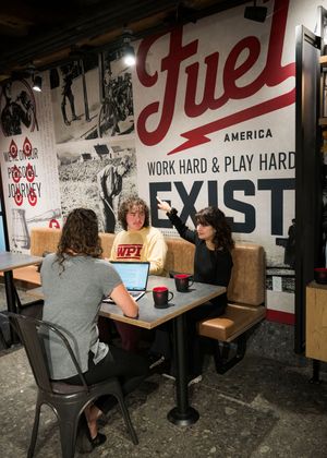 People working at desks in an industrial-style office space with motivational text on walls.