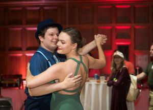 A couple dances together at an event with red ambient lighting in the background.