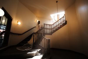 A dramatic staircase in a dimly lit interior with sunlight casting shadows through an elegant chandelier.