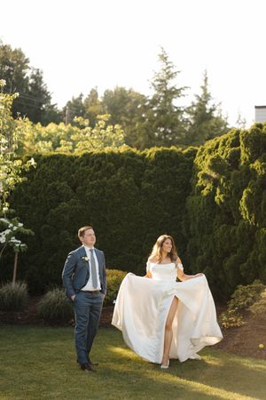 Newlyweds walking together through a garden setting at golden hour with flowing white dress.