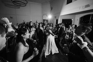 A crowded dance floor filled with party guests dancing and celebrating at a dimly lit indoor venue.