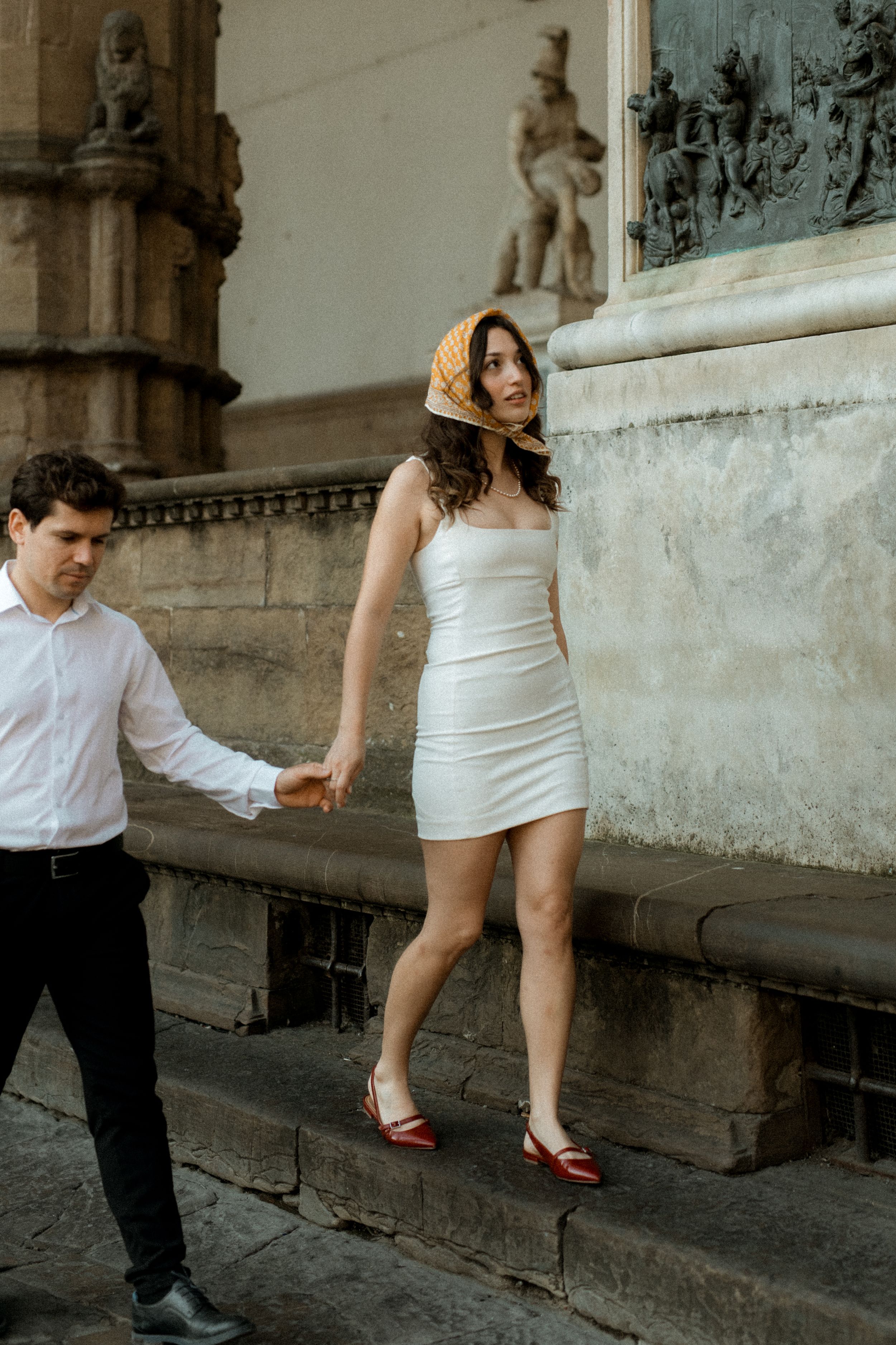 Elopement-kuva jossa juhlavasti pukeutunut hääpari kävelee käsi kädessä portailla Firenzessä Italiassa.