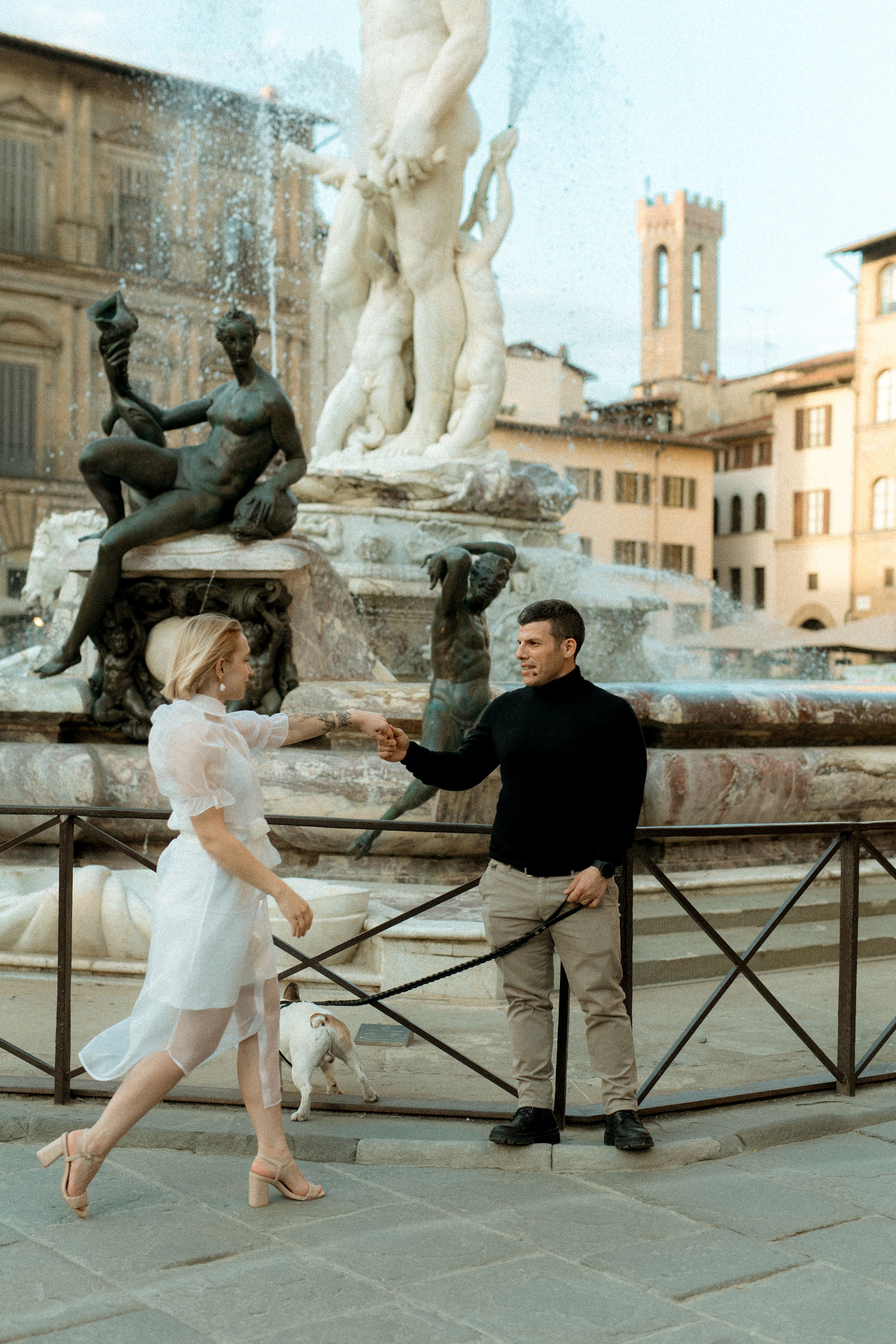 Dokumentaarinen elopement-kuva jossa pariskunta tanssii Neptunuksen suihkulähteen edessä Firenzen Piazza Della Signorialla Italiassa.