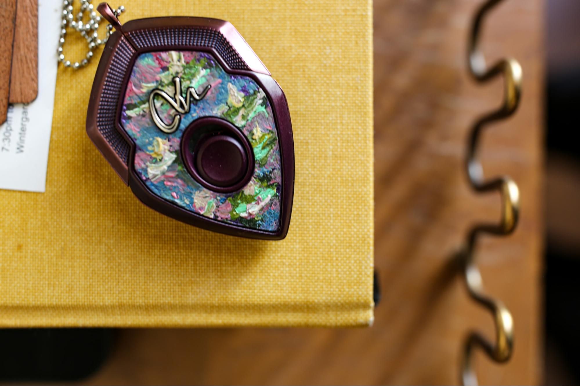 Colorful abalone shell inlaid decorative jewelry pieces arranged on a textured gold background.