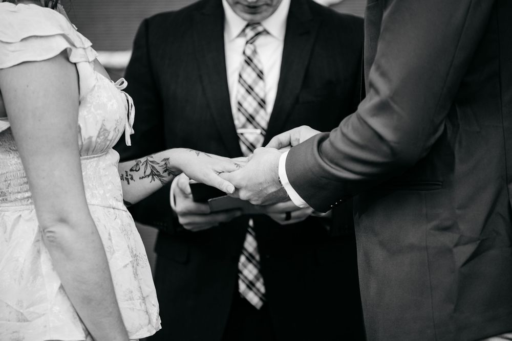 A black and white photo showing hands exchanging a pen and signing papers during a formal business meeting.