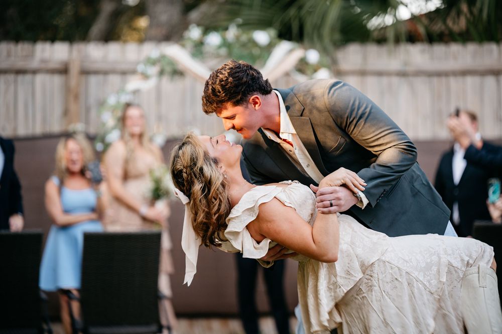 A couple performs a romantic dip during their first dance at an outdoor wedding reception.