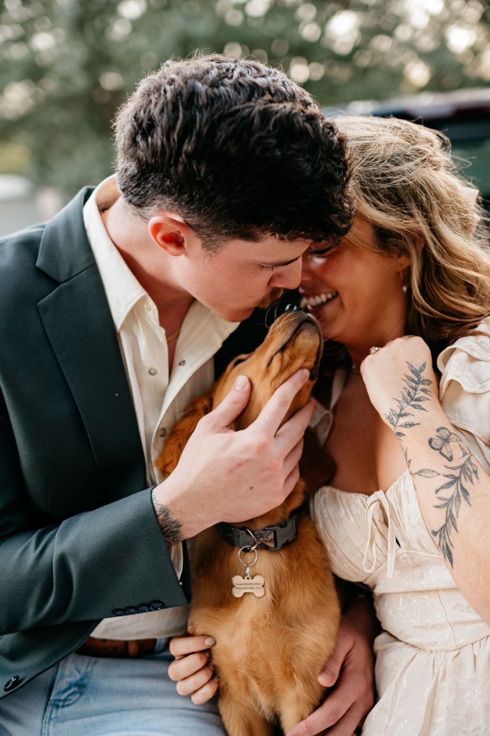 A couple shares an intimate moment with their golden retriever dog during a romantic outdoor photoshoot.
