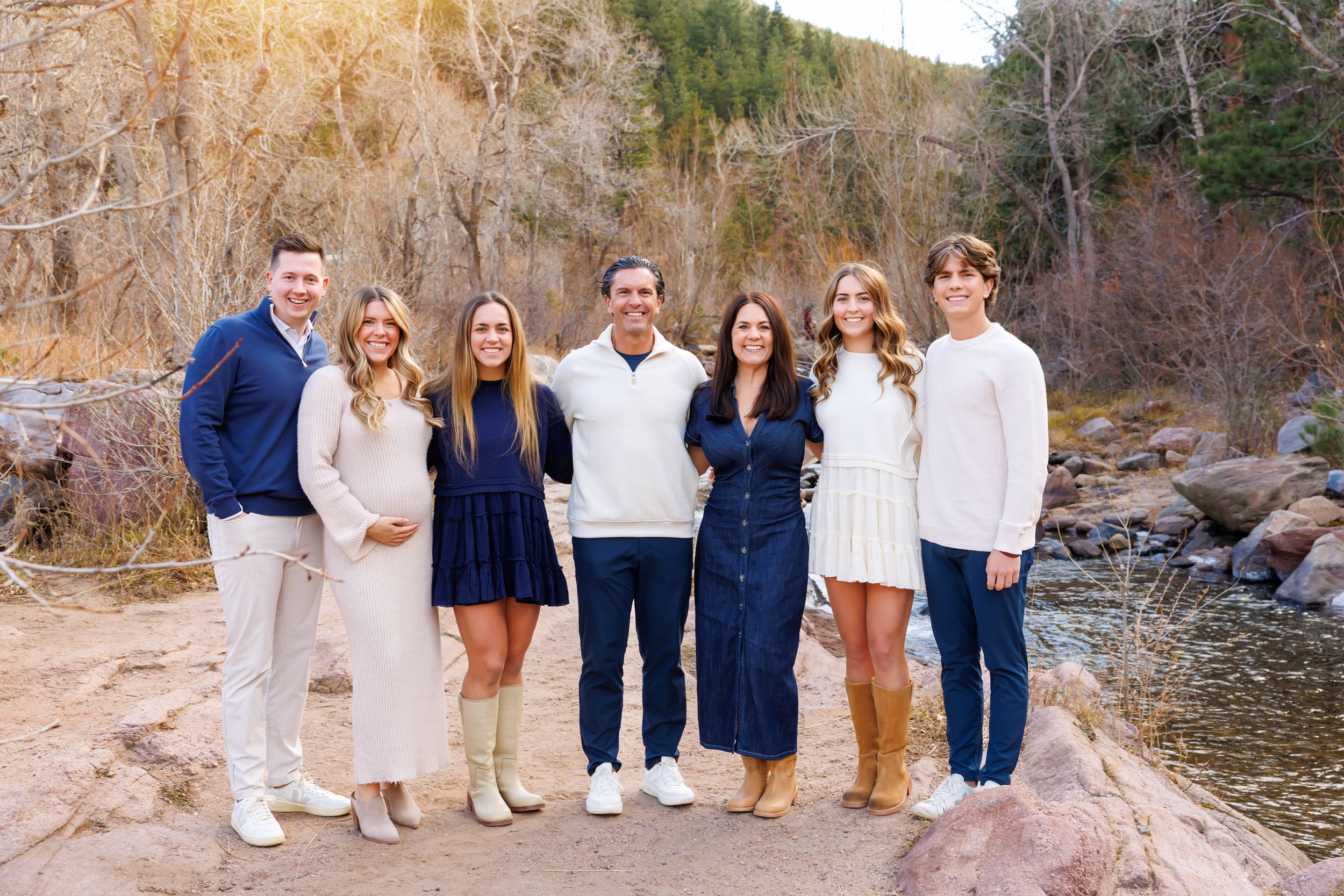 Group poses together on rocky terrain near a mountain stream during fall season.