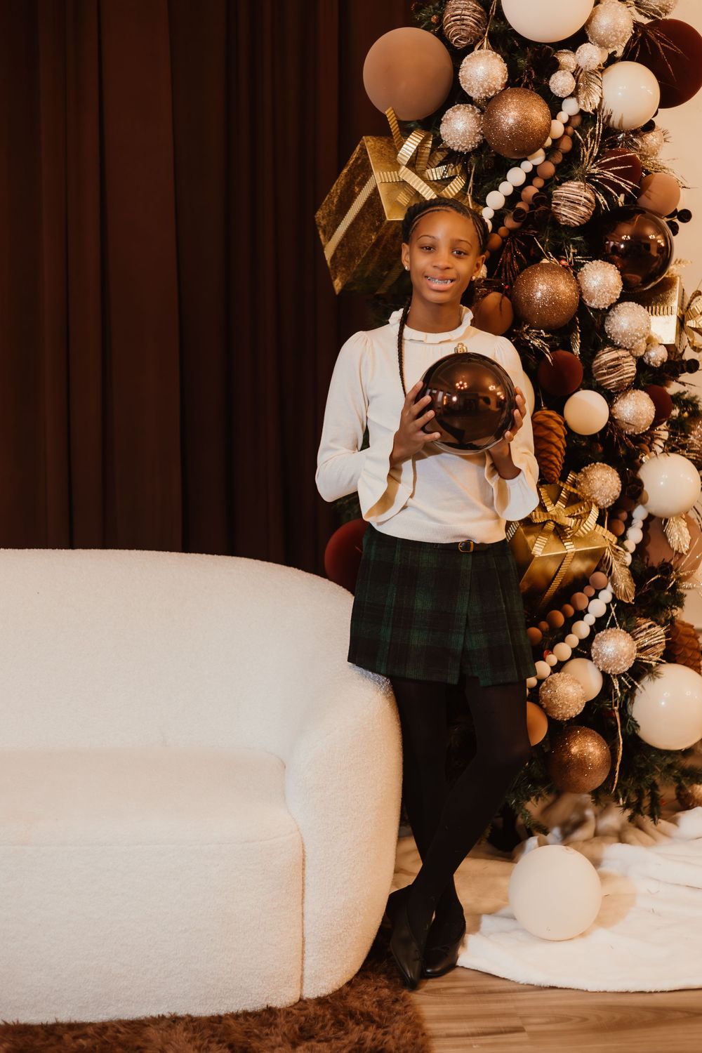 A festive holiday scene with white and gold balloon garlands decorating a corner with plush white seating.