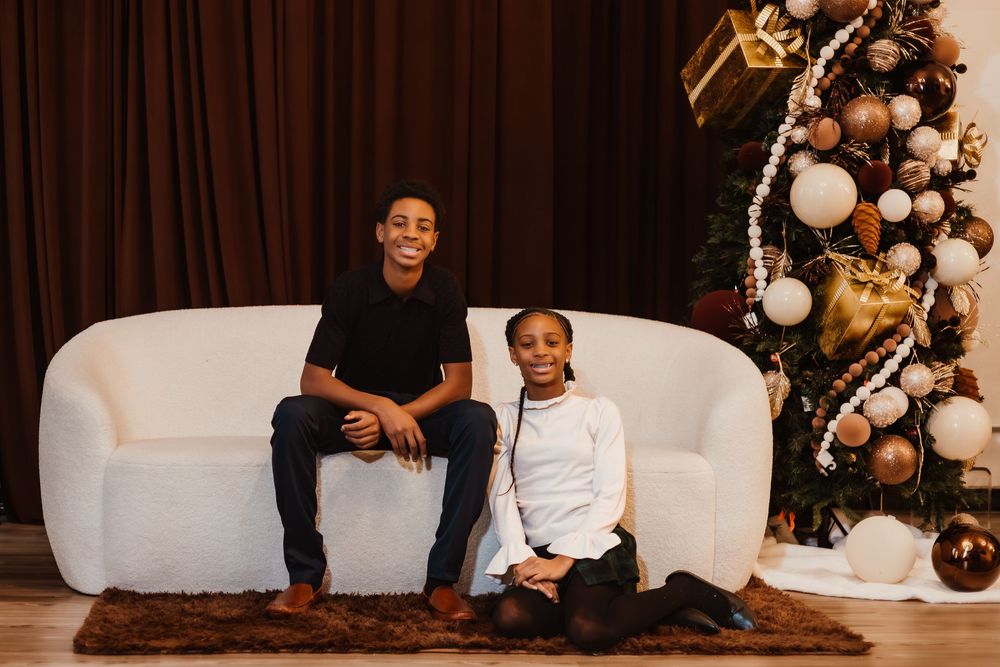 Two people share a joyful moment on a white couch with festive balloon decorations in the background.