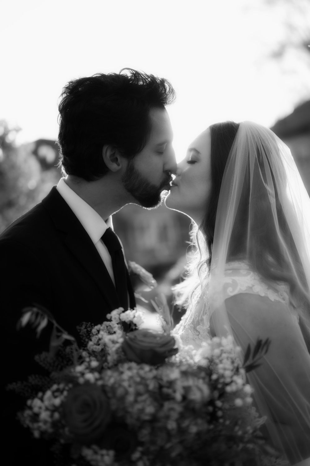 A dreamy black and white photo of a bride and groom kissing during golden hour outside of the Roberts Mansion in Spokane Washington..