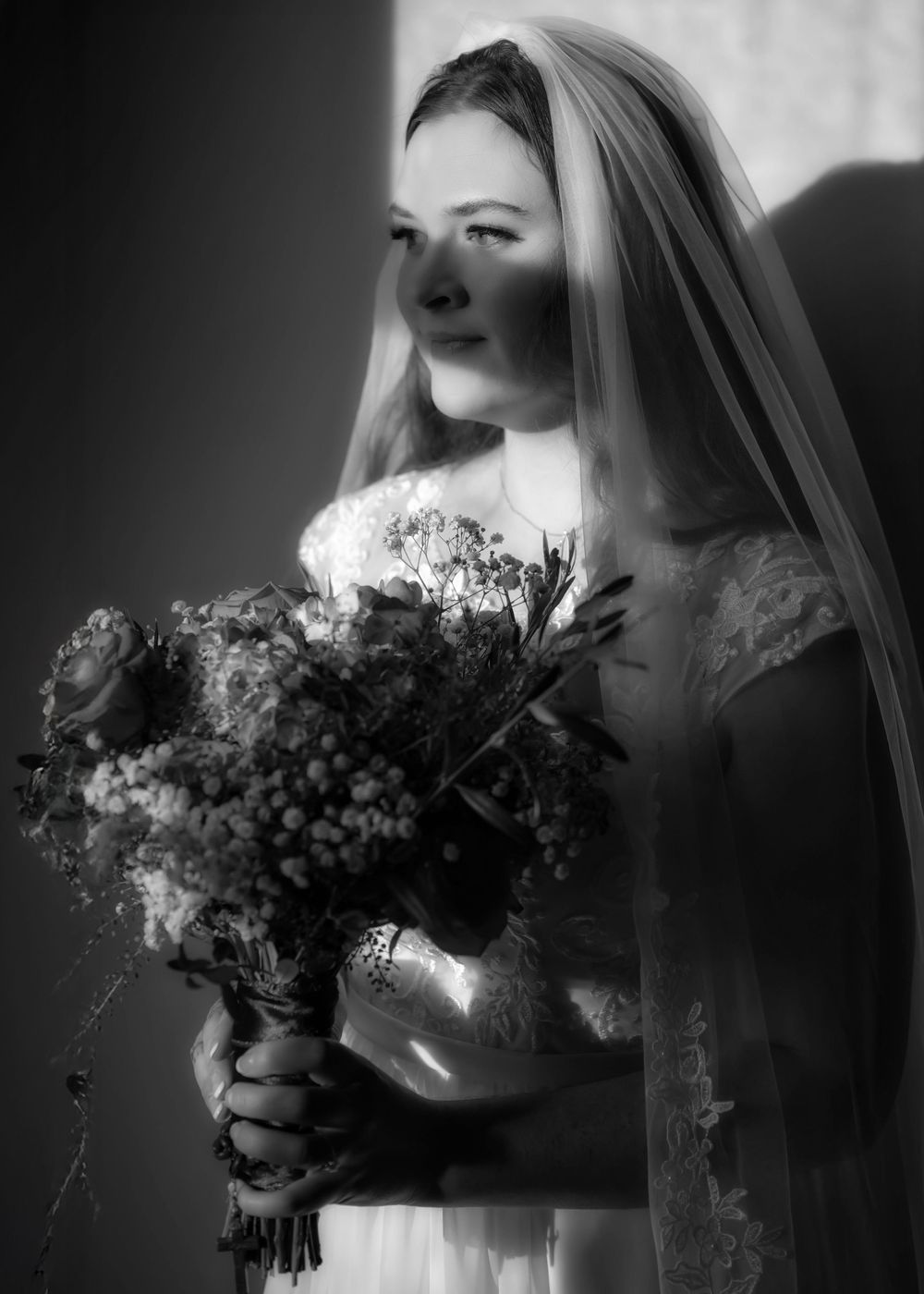 A black and white portrait of a dreamy bride in the golden hour light through a window at the Roberts Mansion.