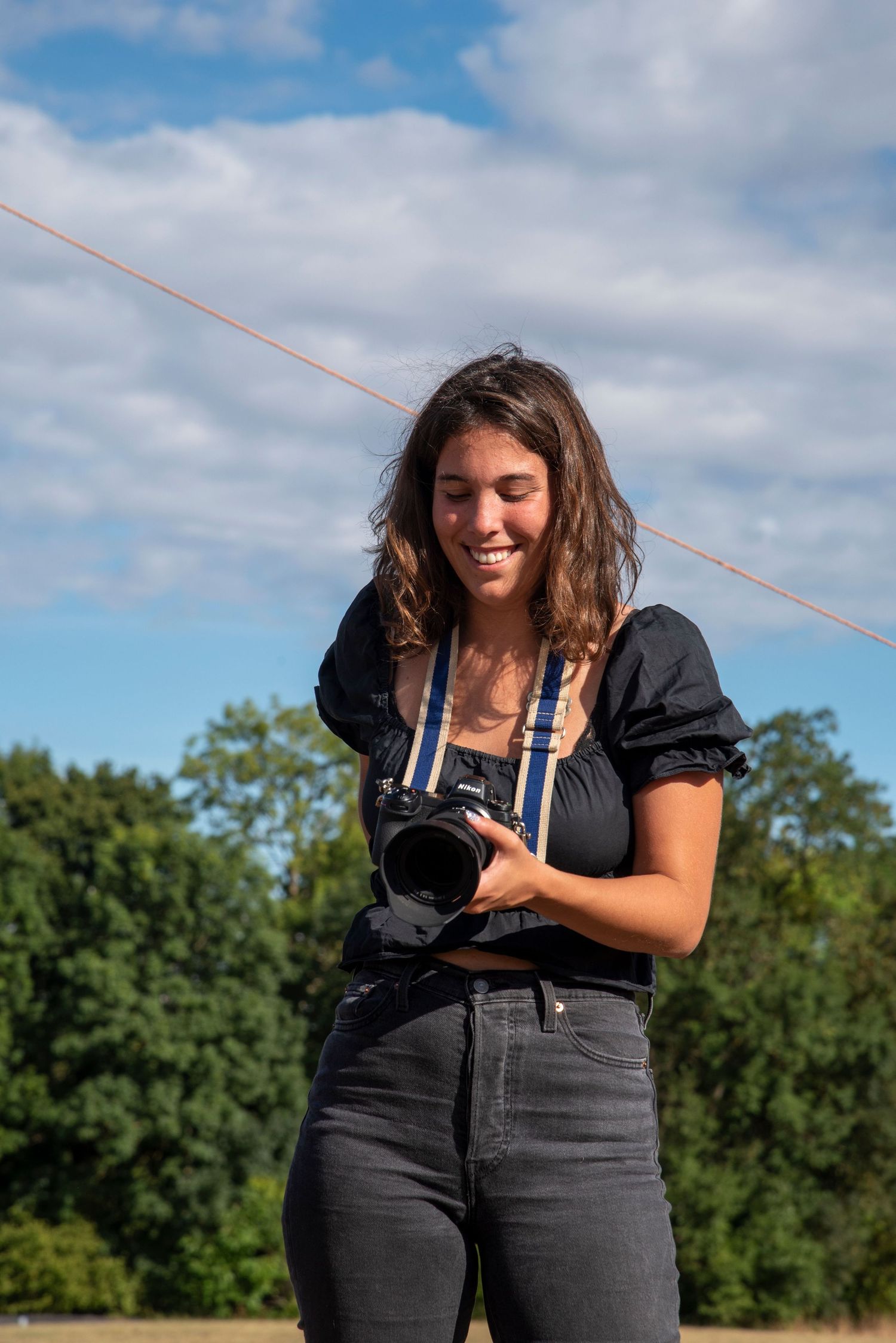 Equestrian and countryside sports photographer holding a camera outdoors on a sunny day, preparing to shoot at a UK event.