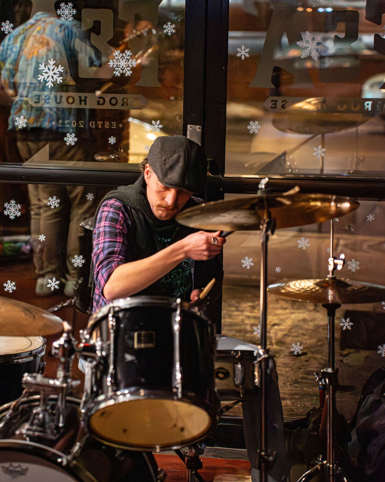 Drummer performing on stage with snowflake decorations visible in the foreground.